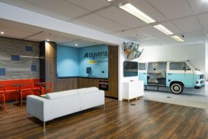 Modern ingerichte kantoorlounge van Ayvens aan de Johan Huizingalaan met zithoek, koffiekeuken en een vergaderruimte in een ingewerkte retro Volkswagenbus.